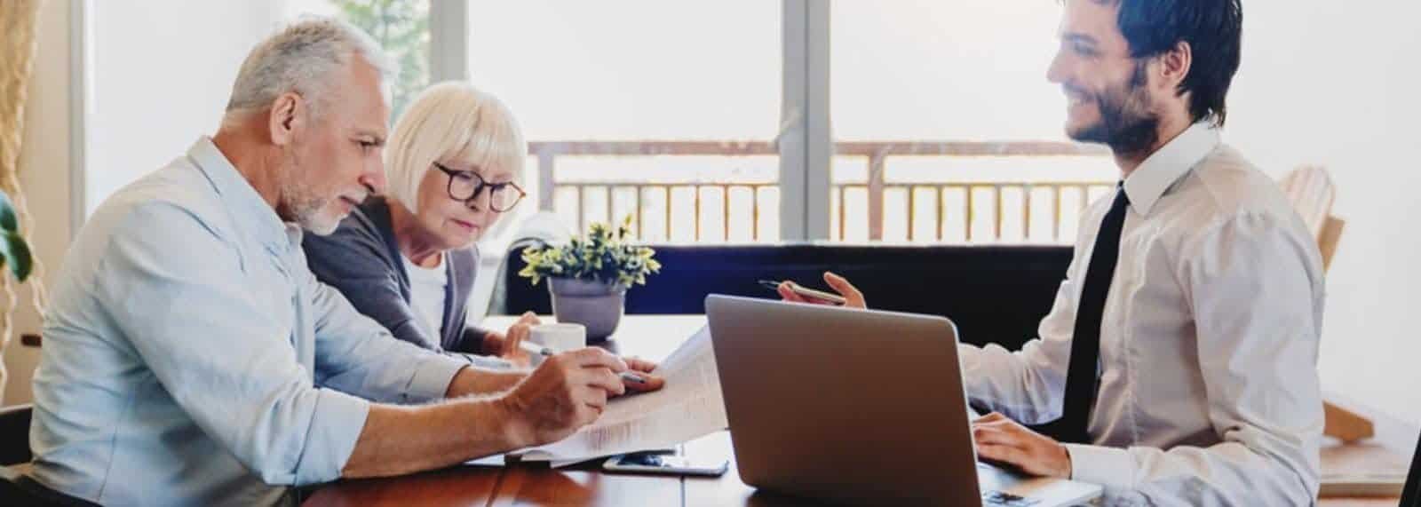 a woman and man sitting at a table with a laptop and a cup of coffee